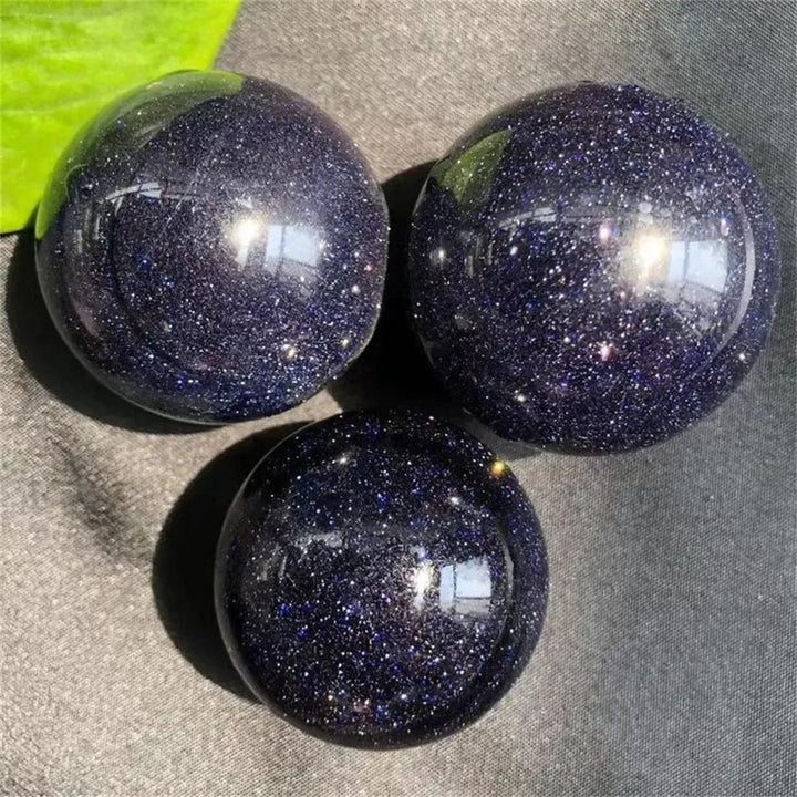 Three polished Blue Sandstone spheres from Crystal Destiny, deep blue with shimmering golden sparkles.