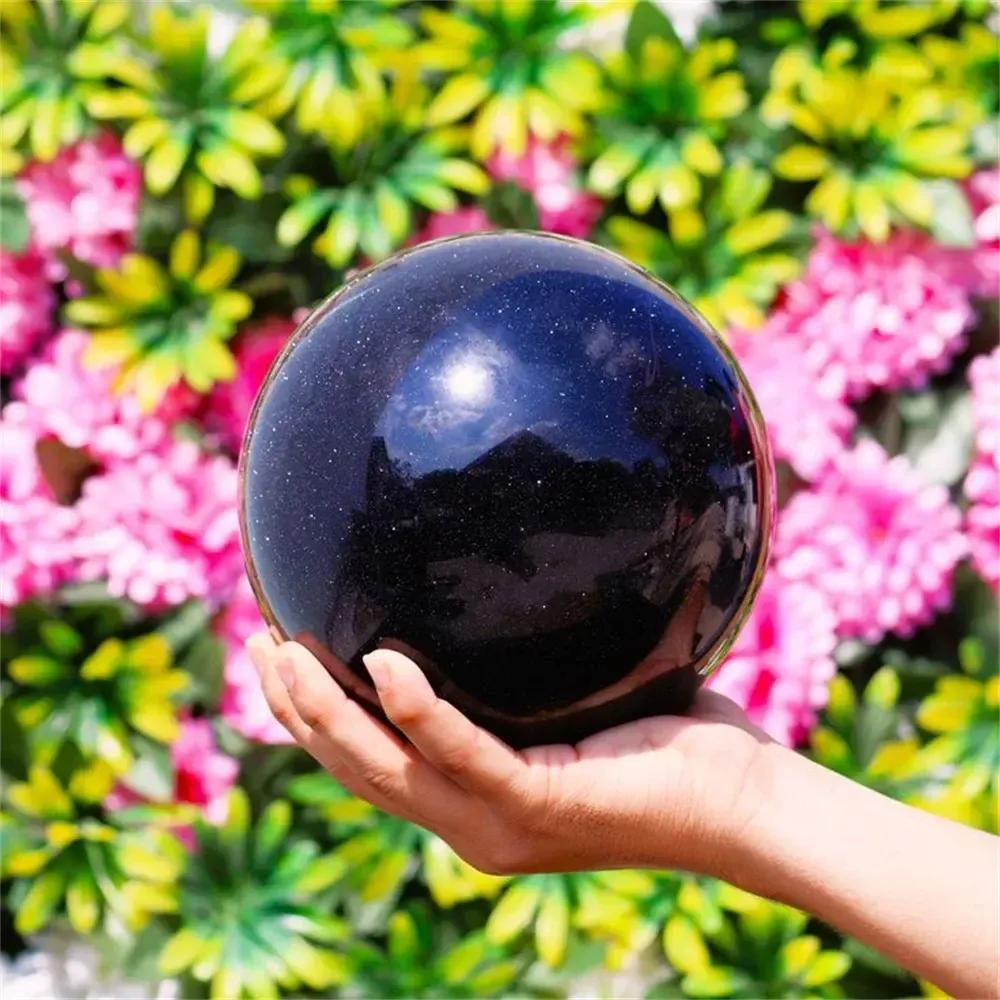 Hand holding a shimmering blue sandstone sphere from Crystal Destiny, inspiring ambition and confidence.