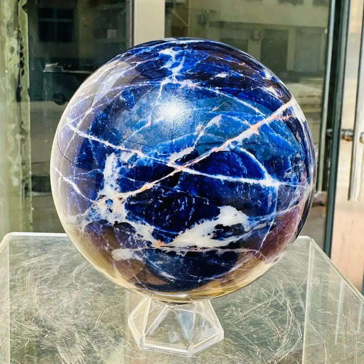 Polished Blue Sodalite sphere featuring deep blue tones and striking white veins, perfect for Throat Chakra healing.