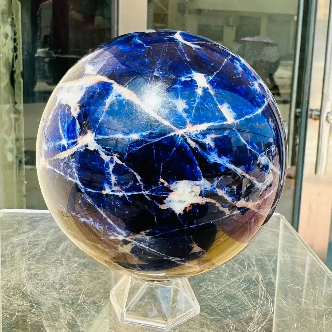Polished Blue Sodalite sphere featuring deep blue tones and striking white veins, perfect for Throat Chakra healing.