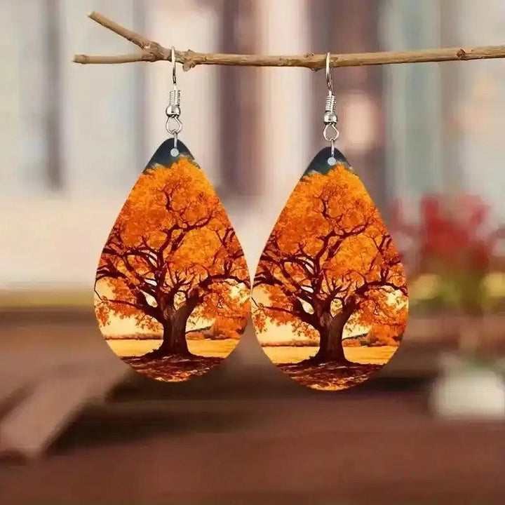 Boho wooden water drop earrings with vibrant orange autumn tree print, hanging from a branch.