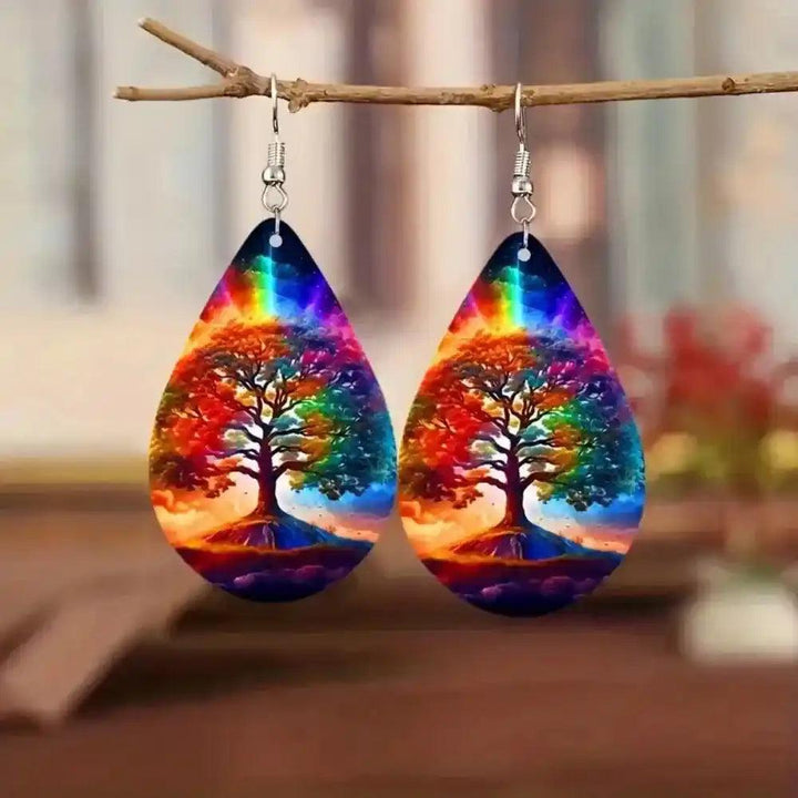 Boho wooden water drop earrings with colorful Tree of Life design and rainbow top, hanging from a branch.