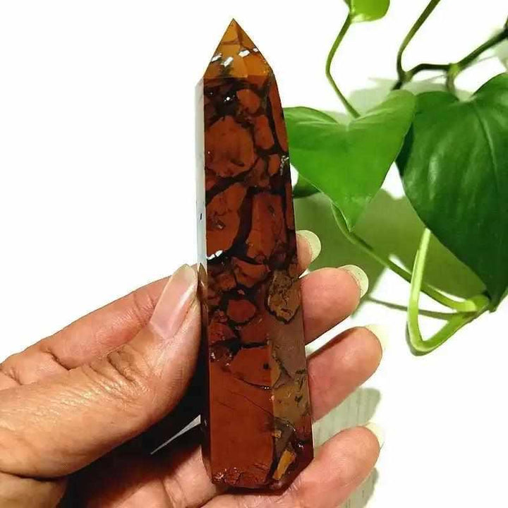 Polished Brecciated Jasper tower with red and brown mosaic patterns for grounding, held in hand for scale.