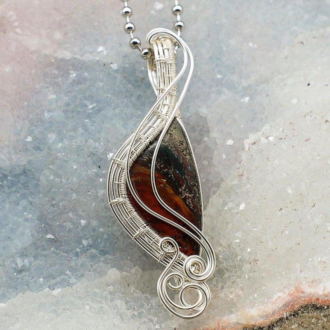 Brecciated Jasper Wire Wrap Pendant: Handcrafted copper wire embraces a mosaic of deep reds, rusty browns, and dark gray.