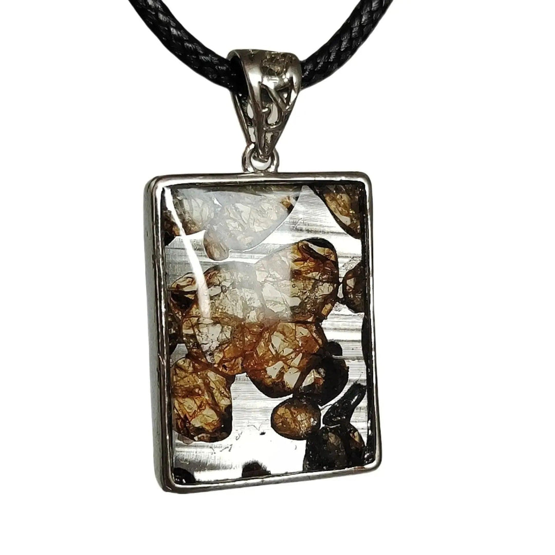 Brenham Meteorite pendant by Crystal Destiny, featuring olive-green peridot crystals in a rectangular sterling silver setting.