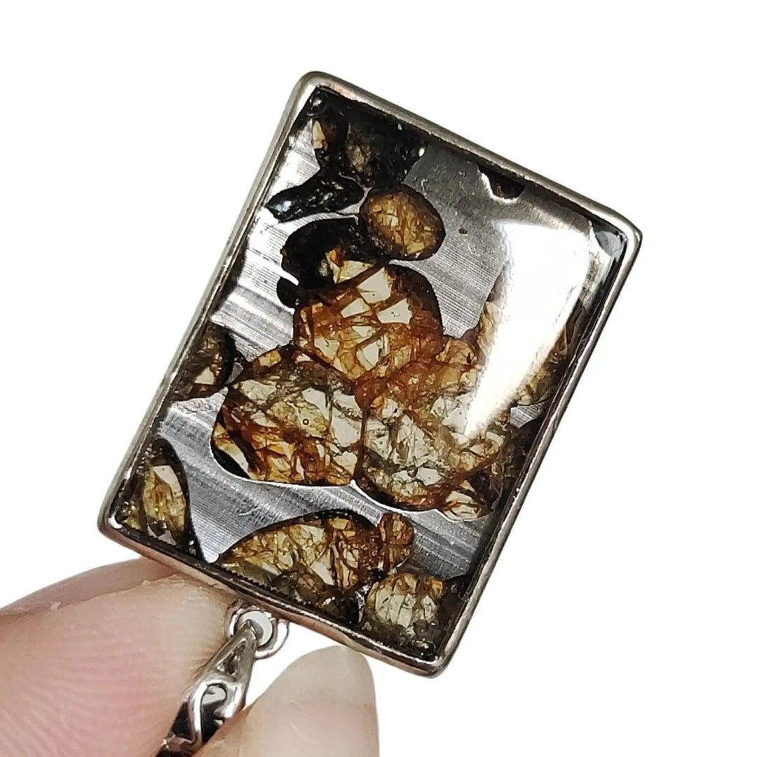Brenham Meteorite pendant with olive-green peridot crystals in a silver setting, from Crystal Destiny.