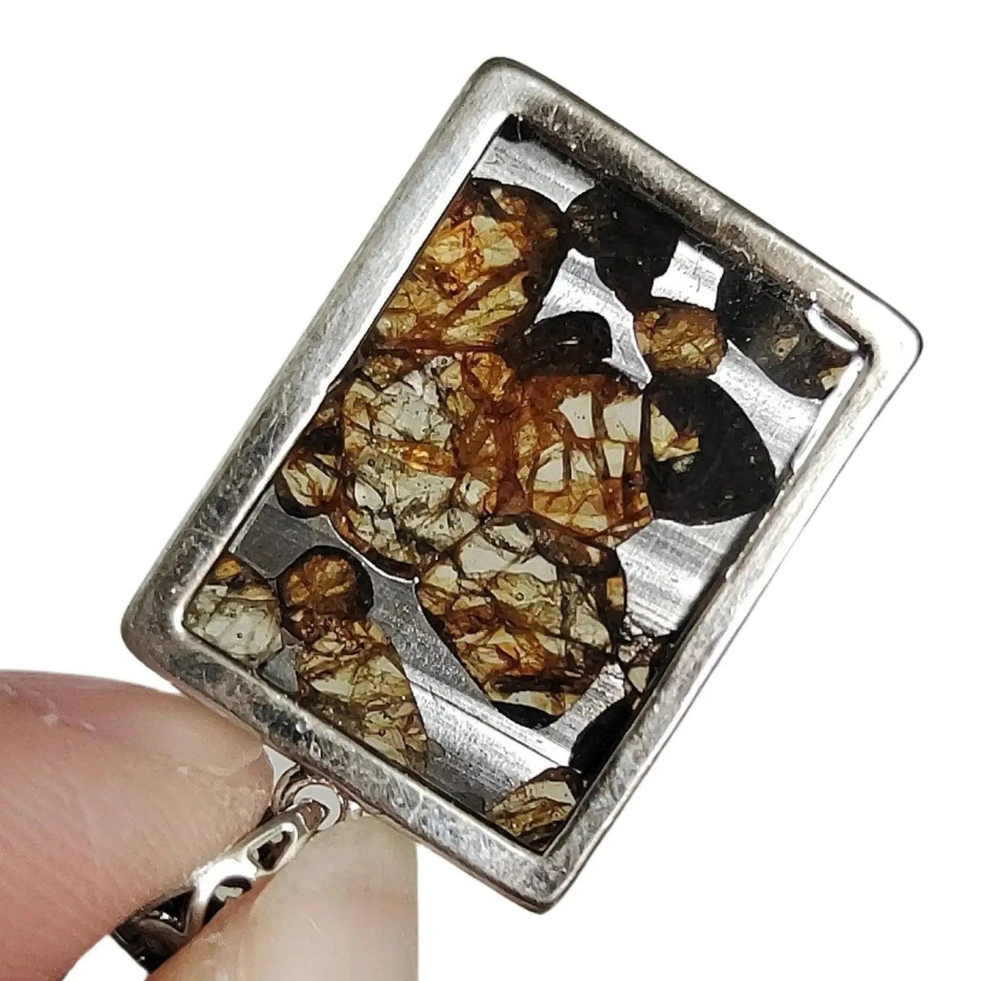 Brenham Meteorite pendant with olive-green peridot crystals in a silver setting, from Crystal Destiny.
