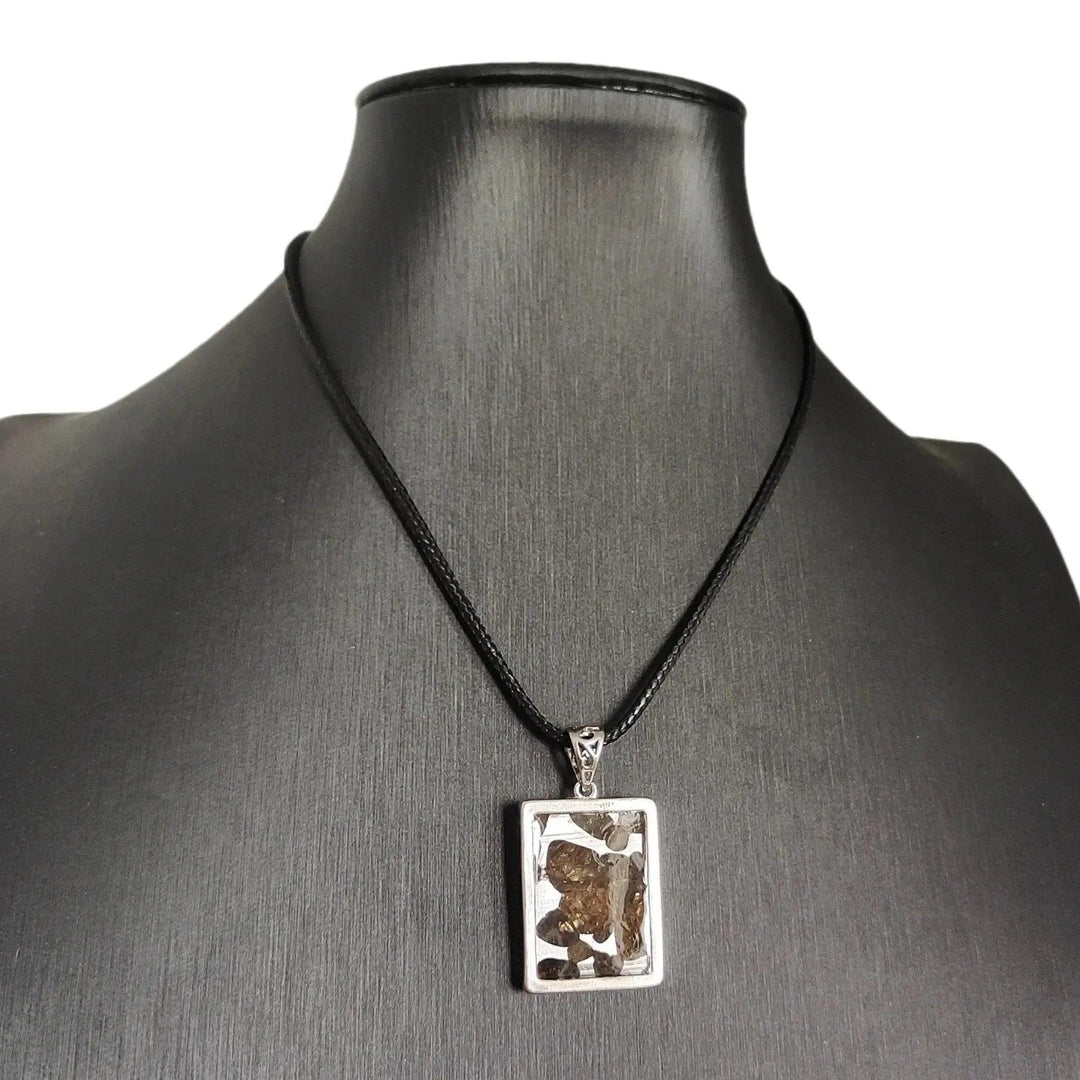 Brenham Meteorite pendant with olive-green peridot crystals in a silver setting on a black cord, by Crystal Destiny.