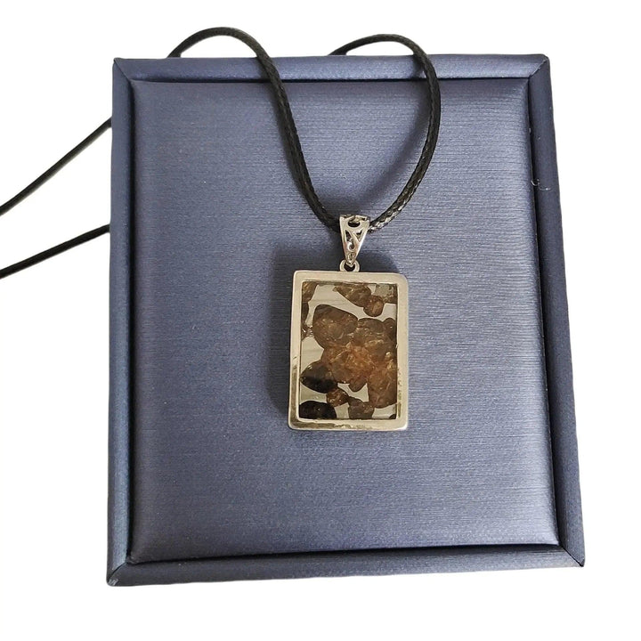 Brenham Meteorite pendant with olive-green peridot crystals in a silver setting on a black cord, from Crystal Destiny.