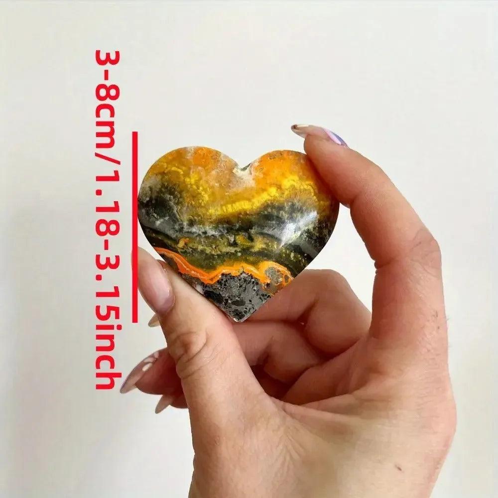 Bumble Bee Jasper Crystal Heart: Vibrant yellow, orange, and black banded heart-shaped crystal, held in hand.