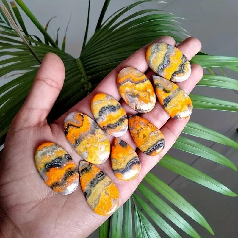 Vibrant yellow and black Bumblebee Jasper Beehive Crystal Palm stones held in hand for healing energy.