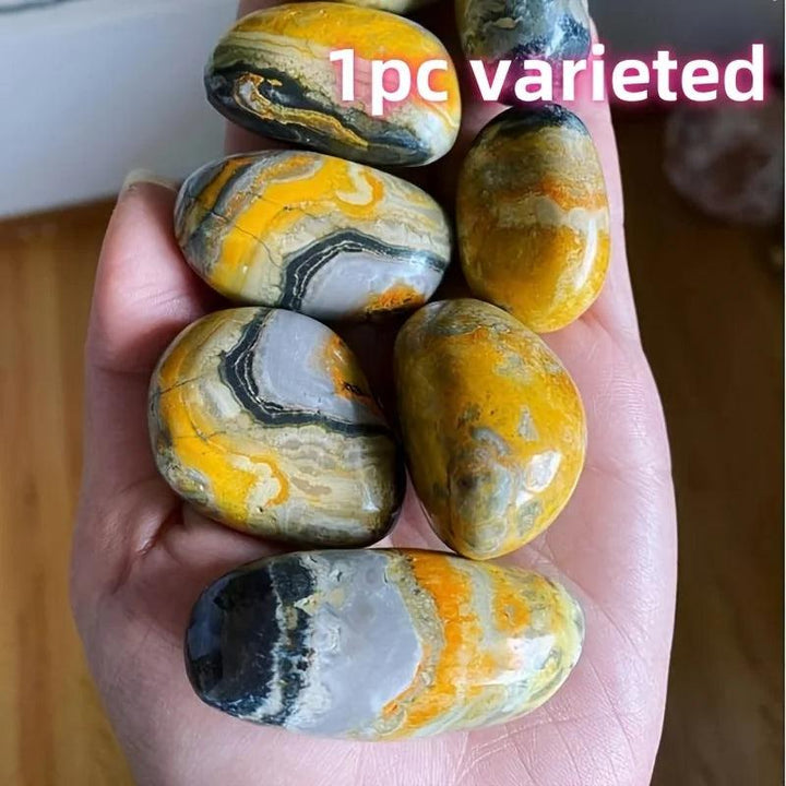 Beehive Crystal Palm stones with vibrant yellow and grey bumblebee jasper patterns held in hand.