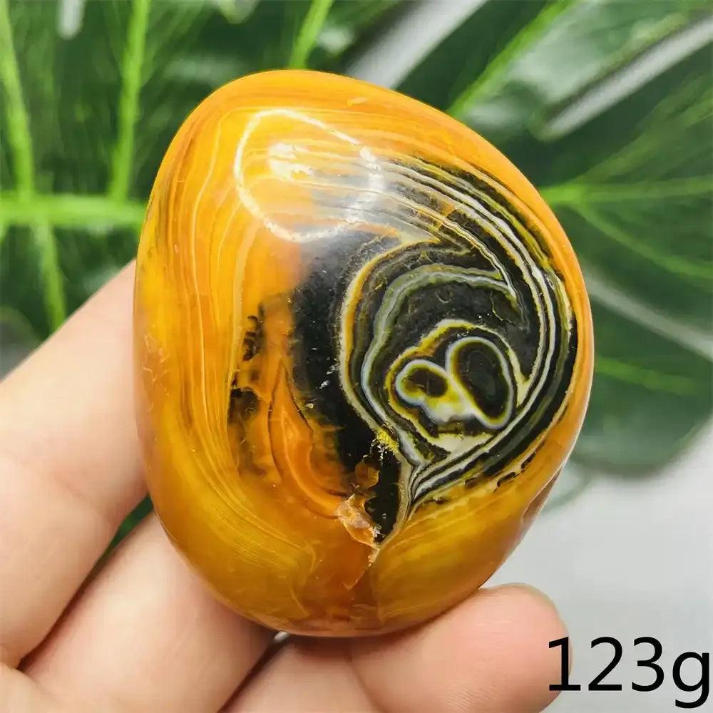 Polished Bumblebee Jasper palm stone with vibrant yellow, orange, and black stripes for Solar Plexus chakra energy.