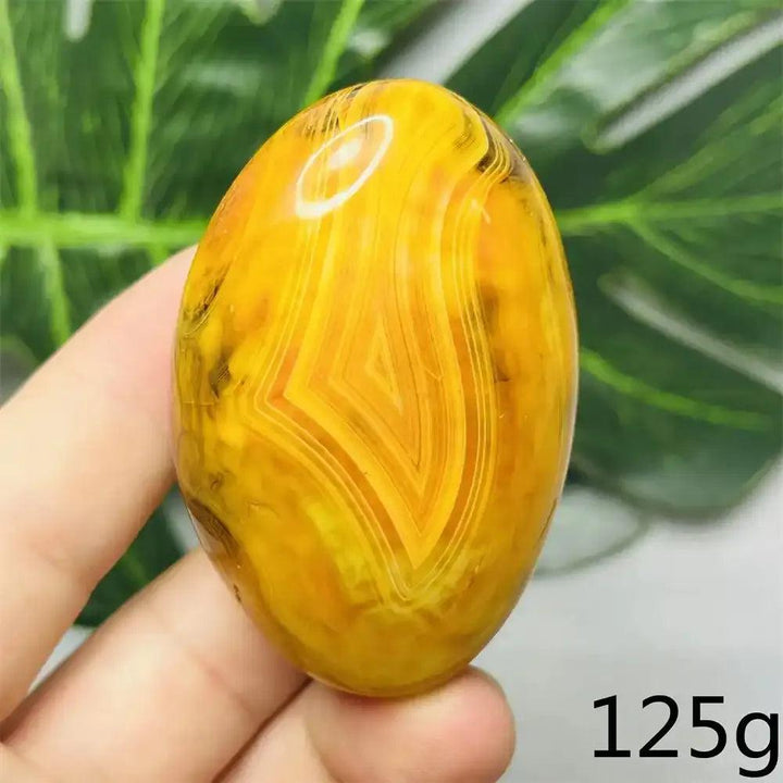 Smooth, hand-polished Bumblebee Jasper palm stone featuring vibrant yellow, orange, and black stripes for solar energy.
