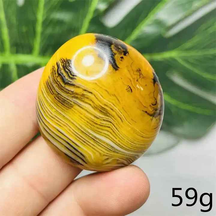 Smooth Bumblebee Jasper palm stone with vibrant yellow, orange, and black stripes for optimism and solar plexus energy.