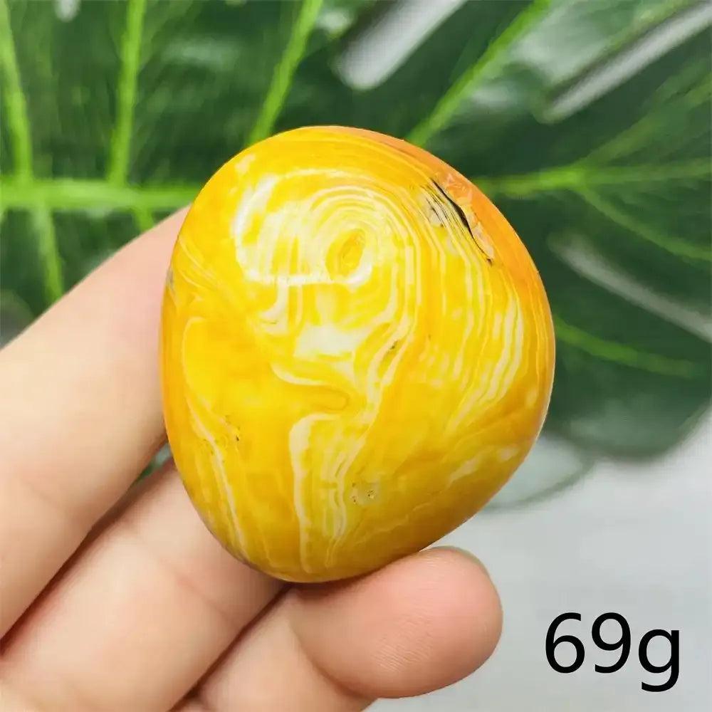 Smooth Bumblebee Jasper palm stone with vibrant yellow, orange, and black stripes for optimism and solar plexus energy.