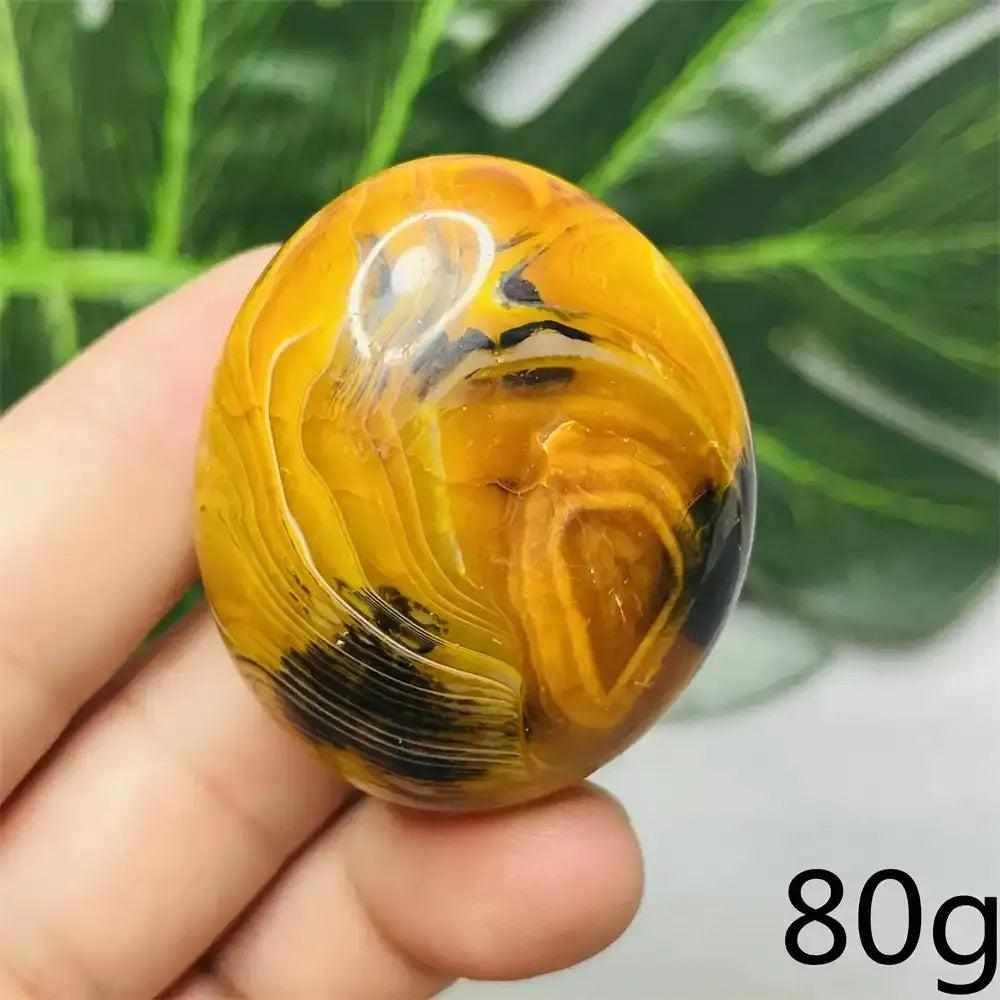 Smooth, hand-polished Bumblebee Jasper palm stone featuring vibrant yellow, orange, and black stripes for solar energy.