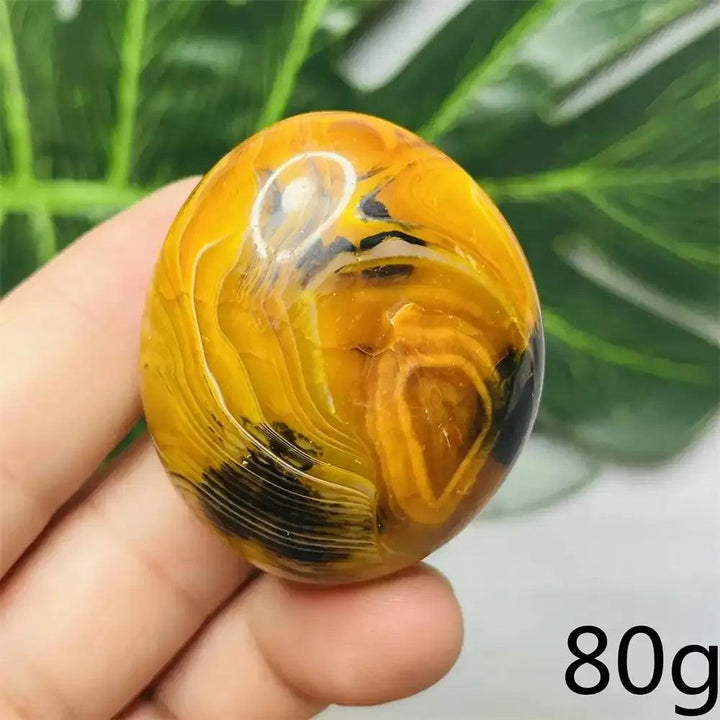 Smooth, hand-polished Bumblebee Jasper palm stone featuring vibrant yellow, orange, and black stripes for solar energy.