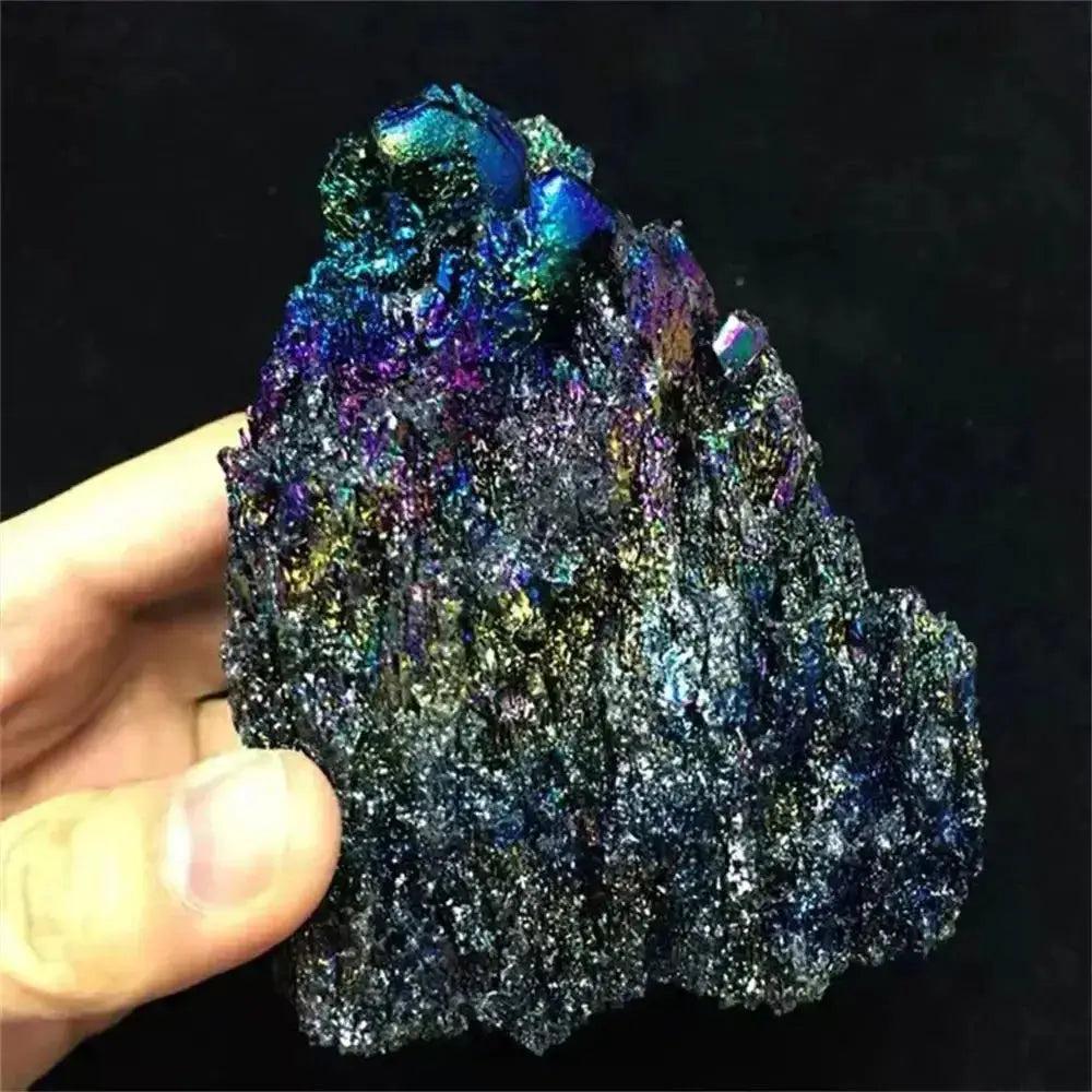 Hand holding a raw Carborundum Silicon Carbide crystal specimen with intense iridescent rainbow surface coloration.