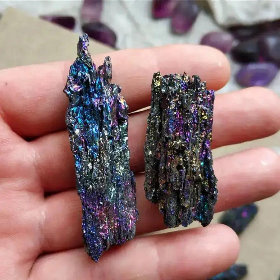 Two raw Carborundum Silicon Carbide crystal specimens, erupting in iridescent rainbow colors, held in a hand.