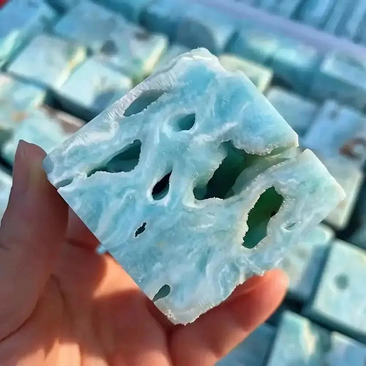 Hand holding a Caribbean Blue Calcite Crystal Cube from Crystal Destiny, showcasing its unique porous texture and calming blue-white swirls.