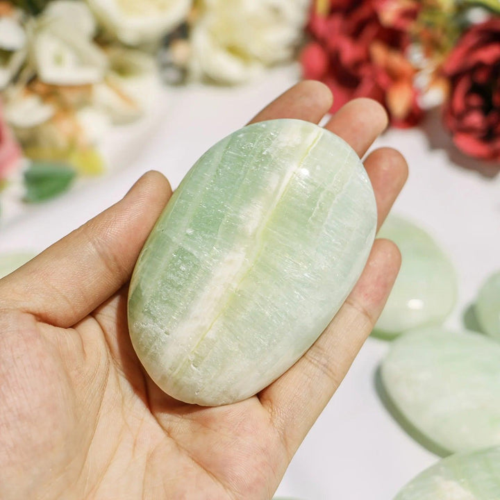 Smooth Caribbean Blue Calcite palm stone with calming pale blue and cream layers, perfect for meditation and relaxation.