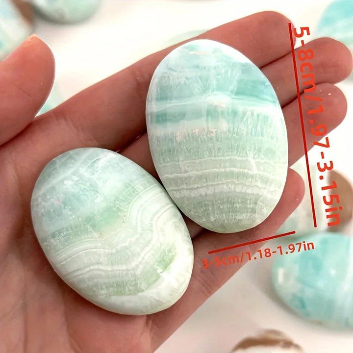 Polished Caribbean Blue Calcite palm stones with calming blue and cream layers, perfect for meditation and tranquility.