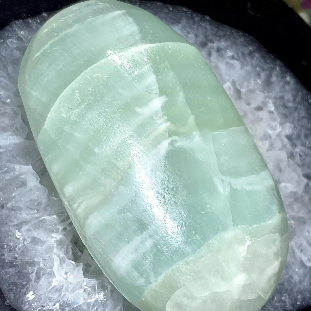 Polished Caribbean Calcite palm stone with soothing ocean blue and white bands for anxiety relief.