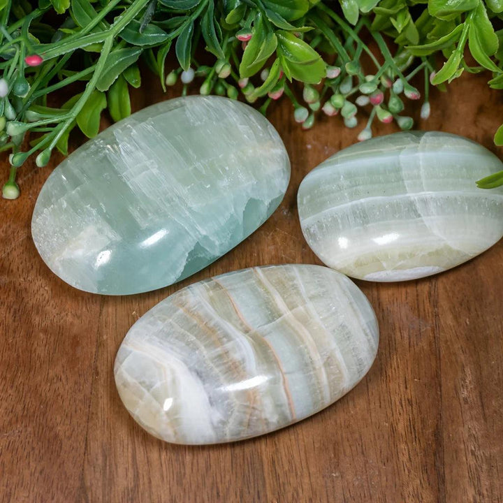 Polished Caribbean Calcite palm stones in soothing ocean blue and tan, perfect for calming anxiety.