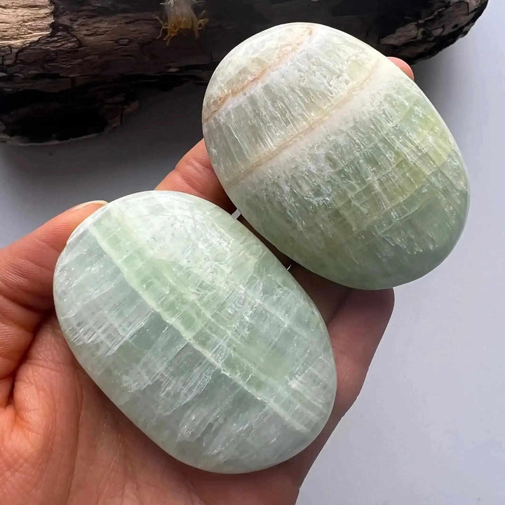 Two smooth Caribbean Calcite palm stones with ocean blue, white, and brown swirls, perfect for calming meditation.