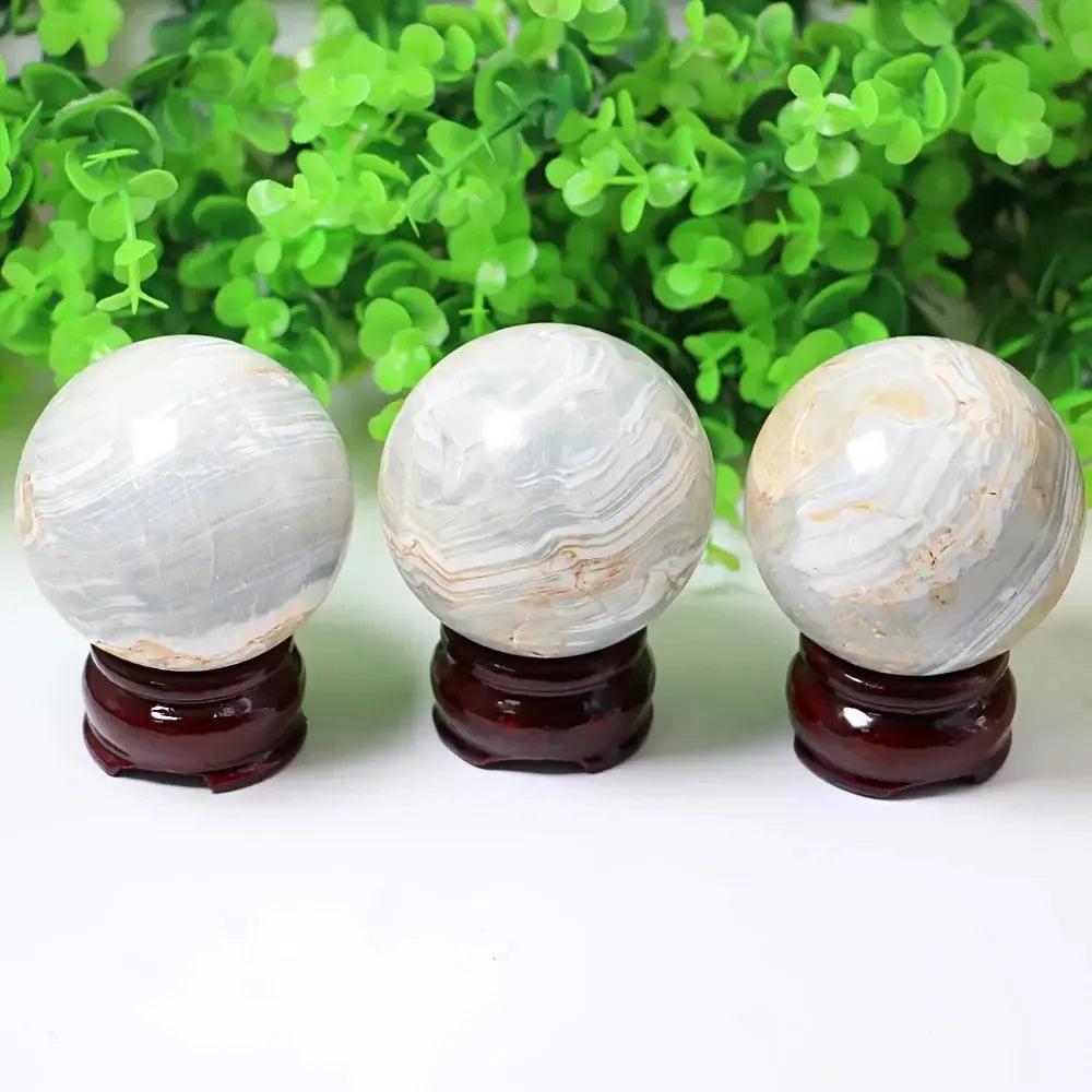 Three Caribbean Calcite spheres from Crystal Destiny, featuring soft blue and white bands on dark wood stands.