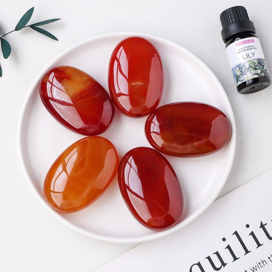 Polished orange-red Carnelian crystal palm stones for grounding, courage, and creativity in a smooth, handheld design.