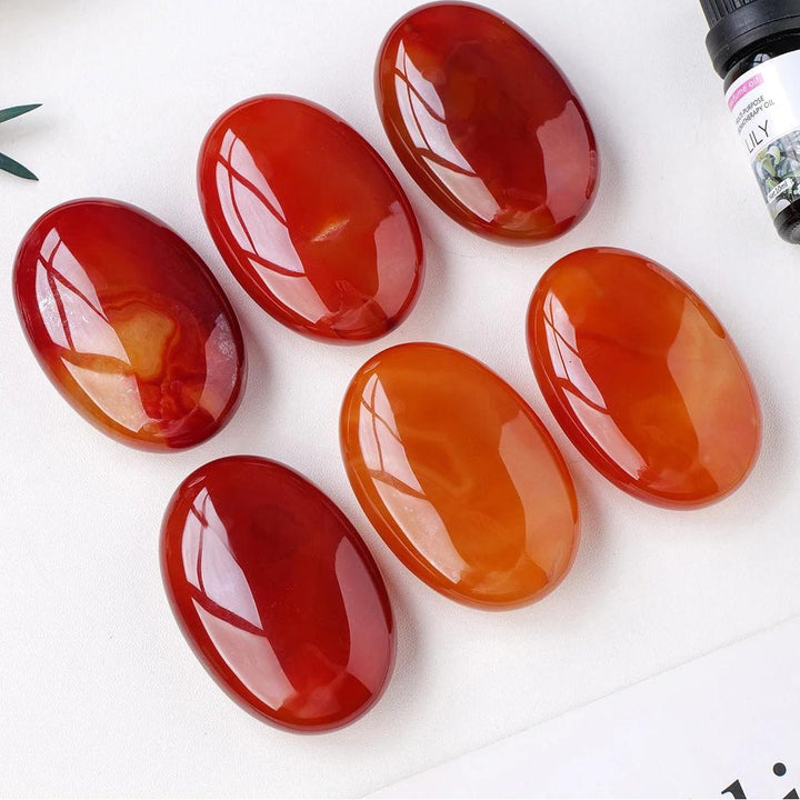 Polished orange-red Carnelian crystal palm stones for grounding, creativity, and courage in a smooth, handheld design.