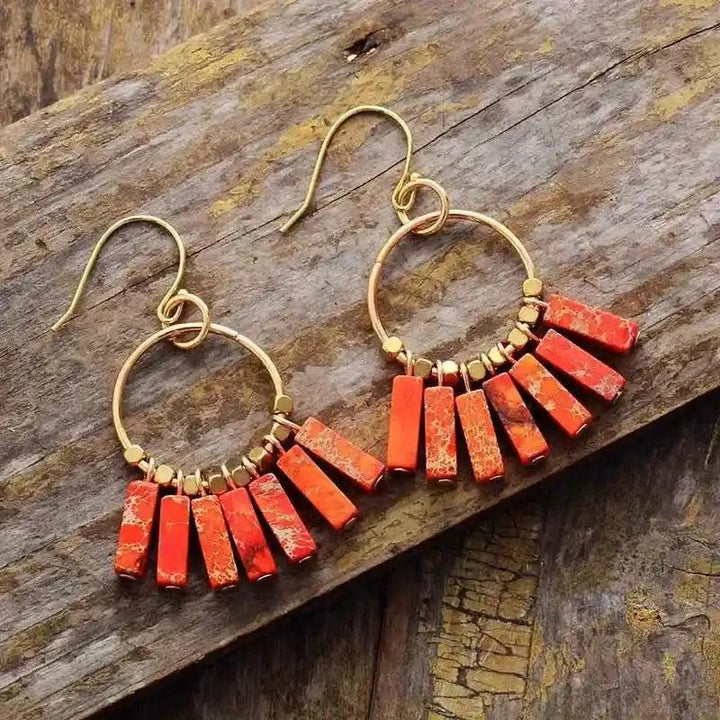 Gold-plated drop earrings with vibrant orange jasper beads, promoting energy and balance.