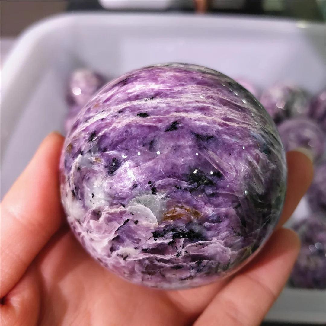Rare Charoite crystal sphere featuring deep violet and lavender swirls with black accents for spiritual transformation.