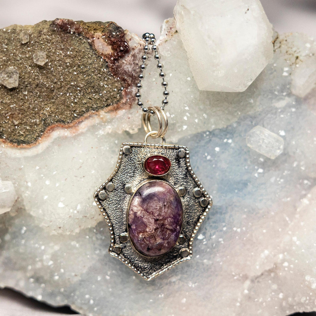 Charoite 925 Sterling Silver Pendant with swirling violet, lavender, and white hues, set with a small red stone.