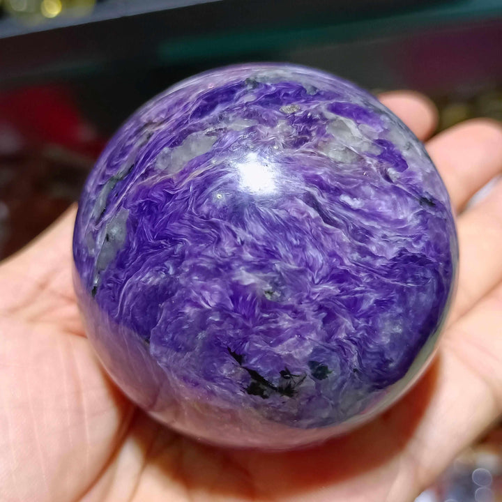 Polished Charoite sphere featuring vibrant violet swirls with white and black accents for spiritual transformation.