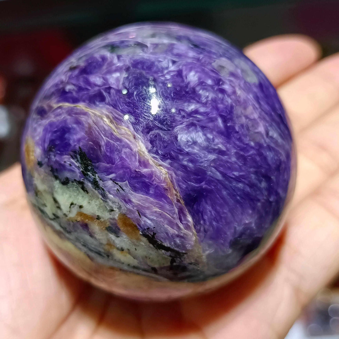 Polished Charoite sphere featuring swirling violet, lavender, and black patterns for spiritual transformation and protection.