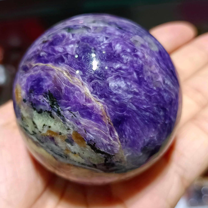Polished Charoite sphere featuring swirling violet, lavender, and black patterns for spiritual transformation and protection.