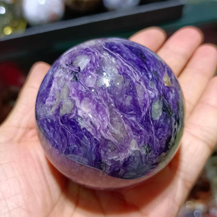 Polished Charoite sphere featuring vibrant violet swirls with white and black accents for spiritual transformation.