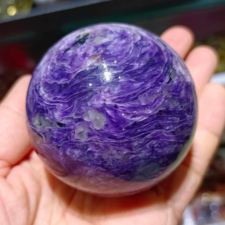 Polished Charoite sphere featuring swirling violet, lavender, and white patterns for spiritual transformation and protection.