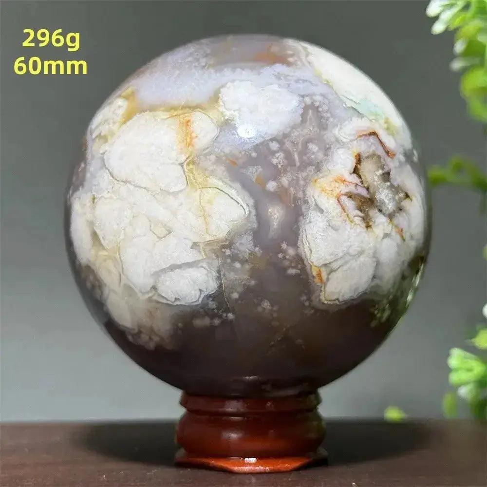 Cherry Agate Crystal Sphere: Polished orb with unique red, pink, and white banding on a wooden base.