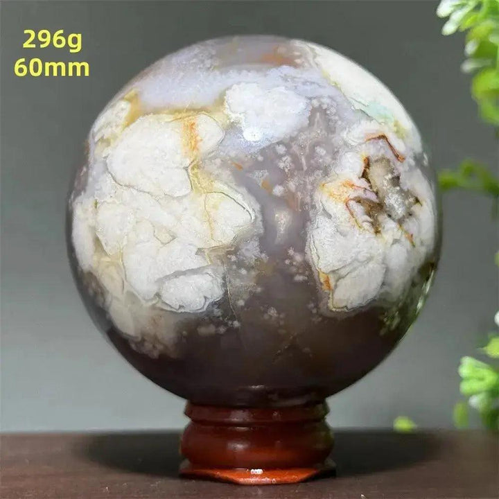 Cherry Agate Crystal Sphere: Polished orb with unique red, pink, and white banding on a wooden base.