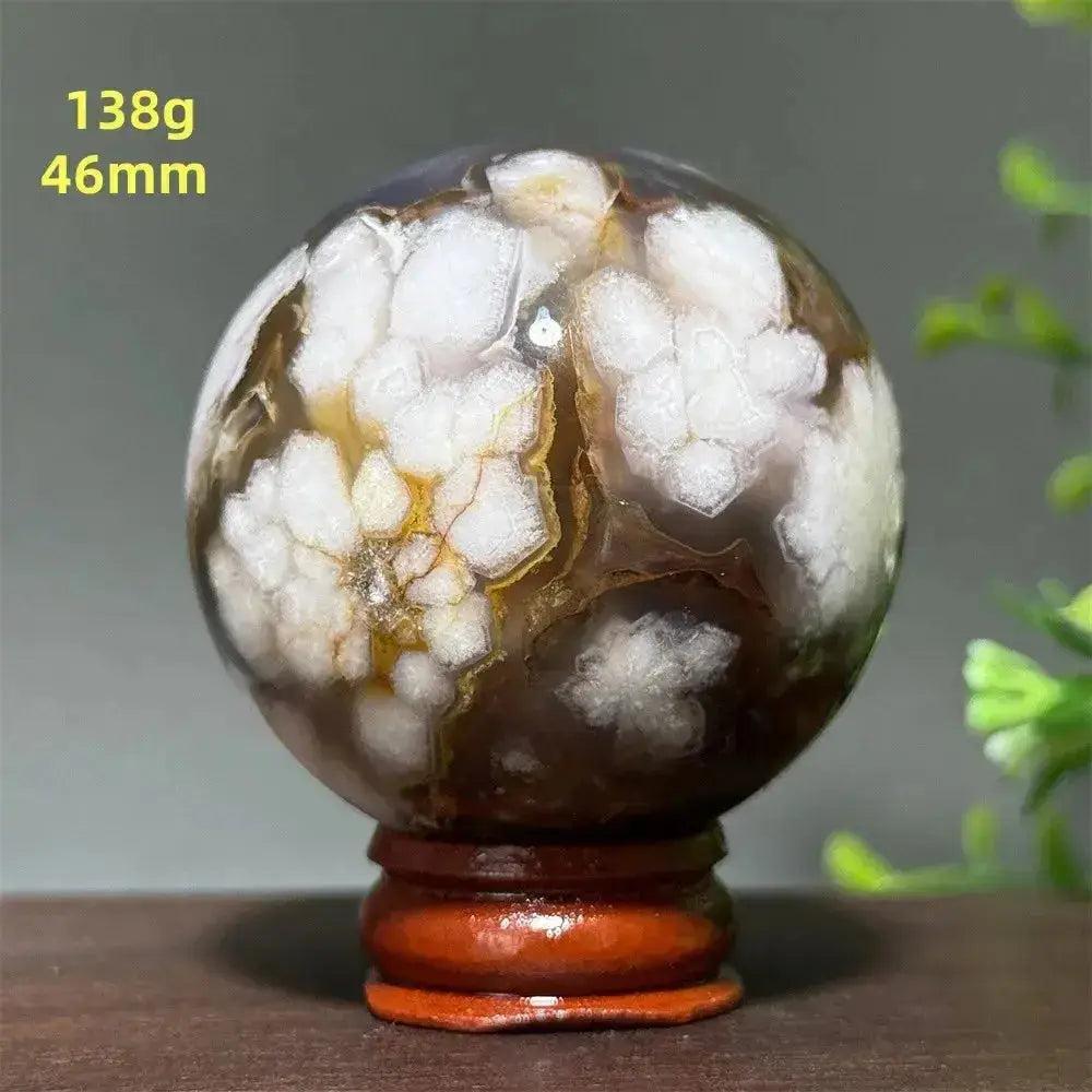 Cherry Agate Crystal Sphere, 46mm, 138g. Polished orb with white floral patterns, brown matrix, and a wooden base.
