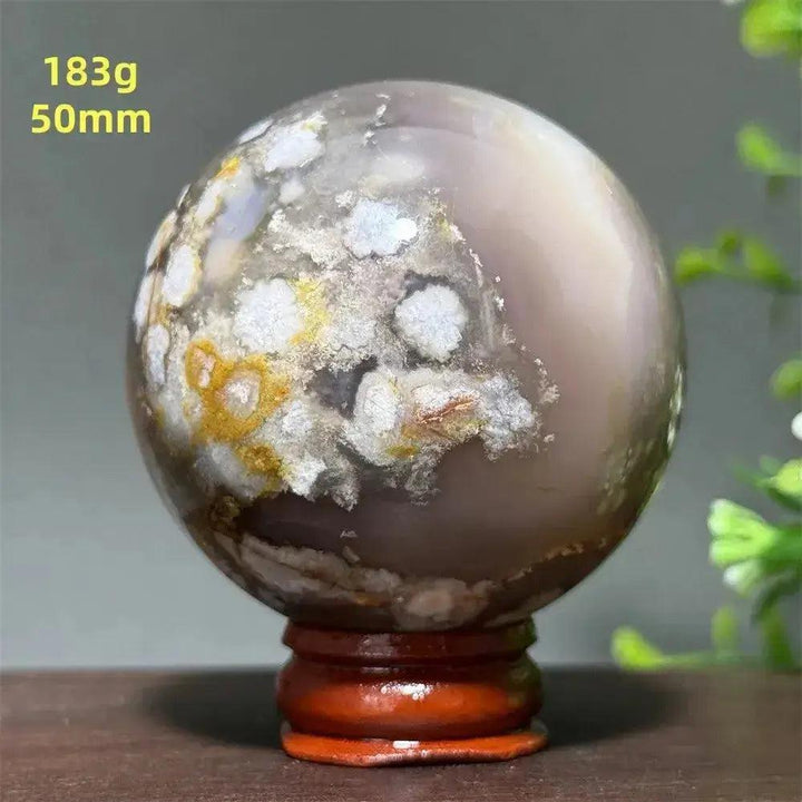 Polished Cherry Agate Crystal Sphere, 50mm, with unique red, pink, and white banding on a wooden base.