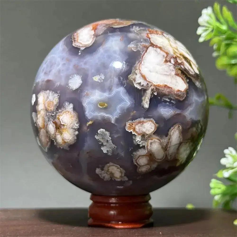 Cherry Agate Crystal Sphere: Polished orb with rich red, pink, and white banding on a wooden base.