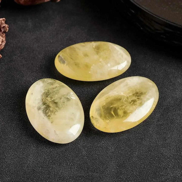 Three polished natural Citrine palm crystals with a smooth, golden yellow finish for Reiki healing and energy balancing.