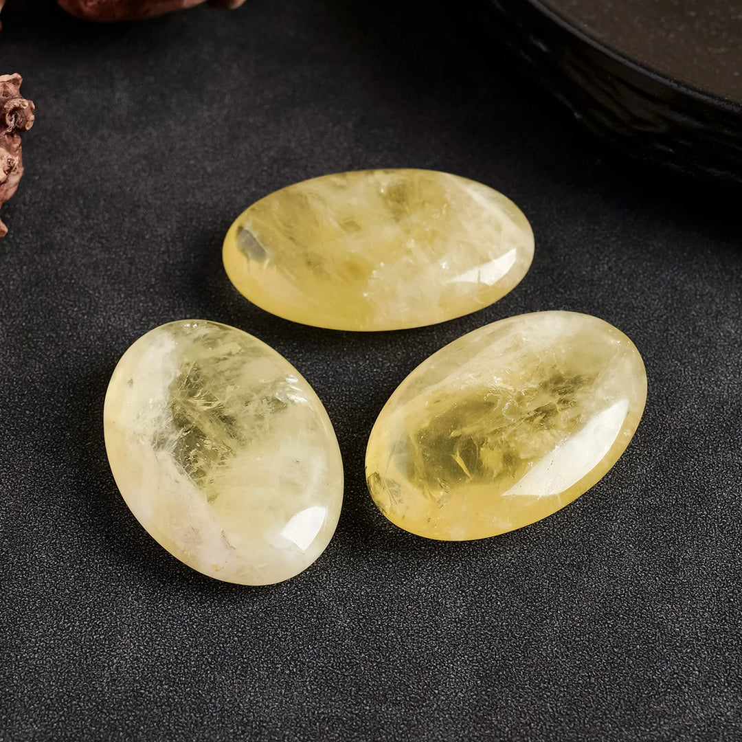 Three polished natural Citrine palm crystals with a smooth, golden yellow finish for Reiki healing and energy balancing.