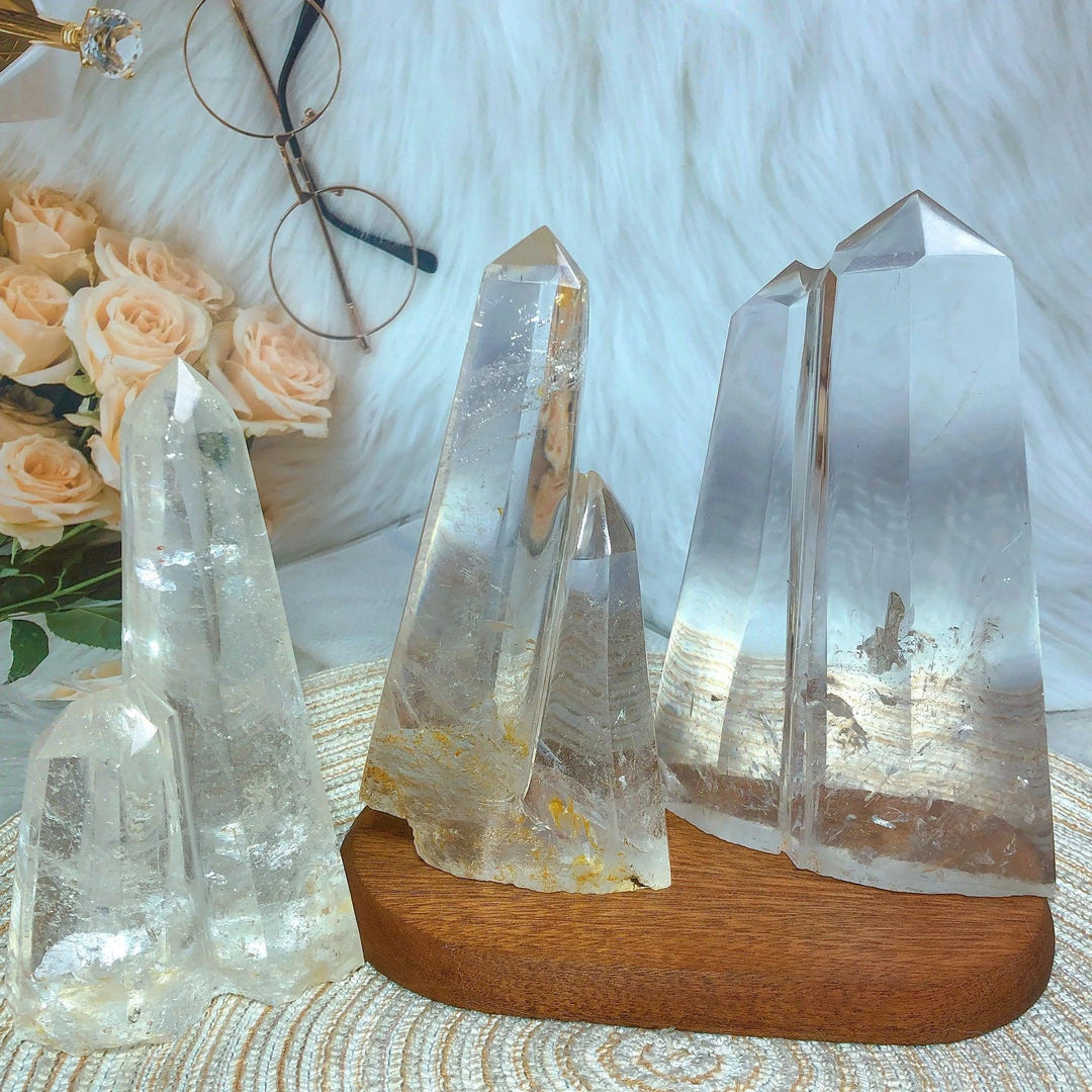 Clear Quartz double mountain tower clusters on a wooden base, with roses and glasses in the background.