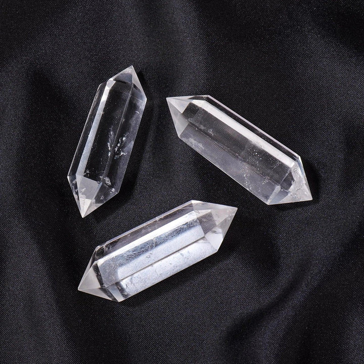 Three clear quartz crystal double terminated points, radiating clarity and amplification on a dark surface.